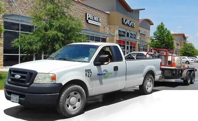 Moore Clean pickup truck and wash trailer parked outside a retail center storefront